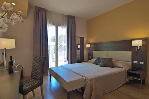 a bedroom with a bed and a chair and a window at Zen Hotel Versilia in Marina di Pietrasanta