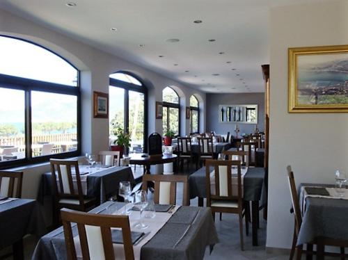 une salle à manger avec tables, chaises et fenêtres dans l'établissement Hôtel Camparellu, à Galéria