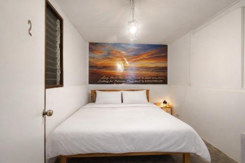 a bed in a room with a painting on the wall at Beatus Residence San Isidro in New Agutaya
