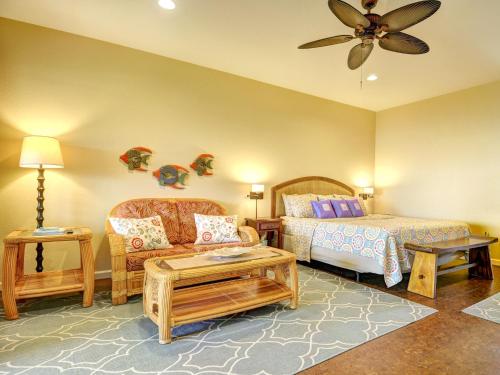 a bedroom with a bed and a couch and a fan at Mahana House Country Inn in North Hilo