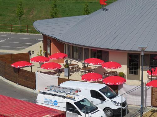 a white van parked in front of a building with red umbrellas at B&B HOTEL Yvetot in Yvetot