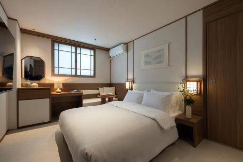 ein Schlafzimmer mit einem großen weißen Bett und einem Fernseher in der Unterkunft Hotel Flow-er in Kangnŭng-yŏk