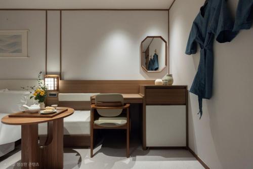 ein Schlafzimmer mit einem Bett, einem Tisch und einem Spiegel in der Unterkunft Hotel Flow-er in Kangnŭng-yŏk