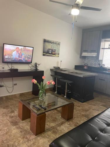 ein Wohnzimmer mit einem Tisch und einem Fernseher an der Wand in der Unterkunft Loft B in Mexicali