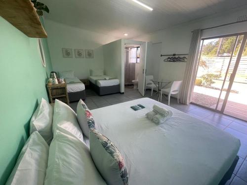 a bedroom with a large white bed in a room at Forest Gate Apartments and Rooms in Plettenberg Bay