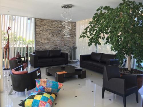 a living room with black furniture and a tree at La Mirage in Villa Gesell