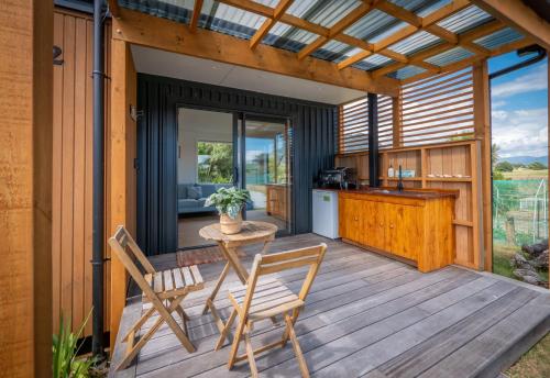 a patio with a table and chairs on a deck at Pohara Beach Pukeko Studio in Pohara