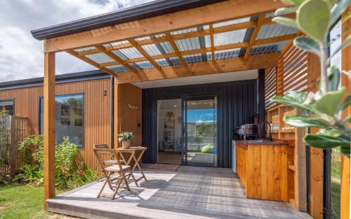 a pergola over a deck with a table and chairs at Pohara Beach Pukeko Studio in Pohara