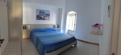 1 dormitorio con 1 cama con edredón azul y ventana en Appartamento Le Tre Volte, en Matera