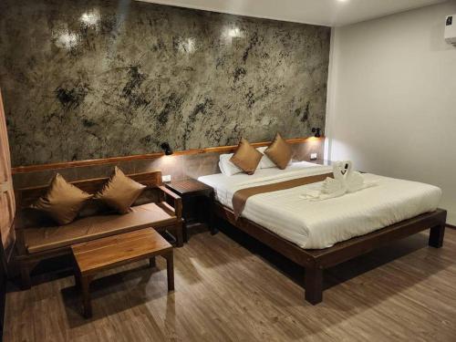 a hotel room with two beds and a bench at Bu-Gaan Sukhothai Village in Sukhothai