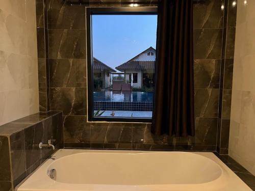 a bath tub in a bathroom with a window at Bu-Gaan Sukhothai Village in Sukhothai