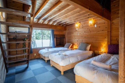 a room with three beds in a log cabin at sneaky peaks in Hakuba