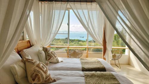 a bedroom with a bed in front of a large window at Hummocks in Sesoko