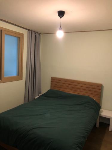 a bedroom with a green bed and a window at 산초리니 Sanchorini in Busan