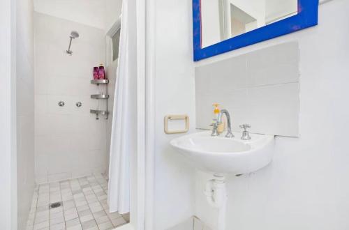 a white bathroom with a sink and a shower at Ocean Studio along Shelly Beach in Sydney