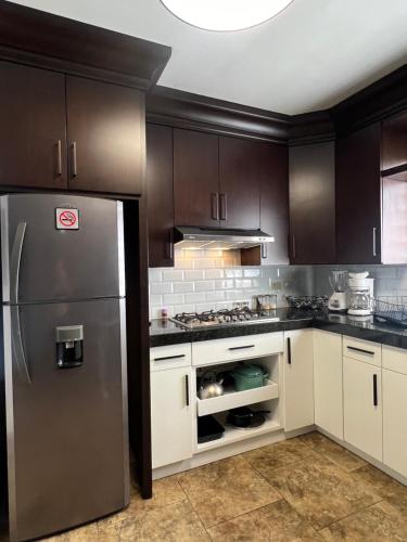 a kitchen with white cabinets and a stainless steel refrigerator at Loft A cerca zona dorada in Mexicali