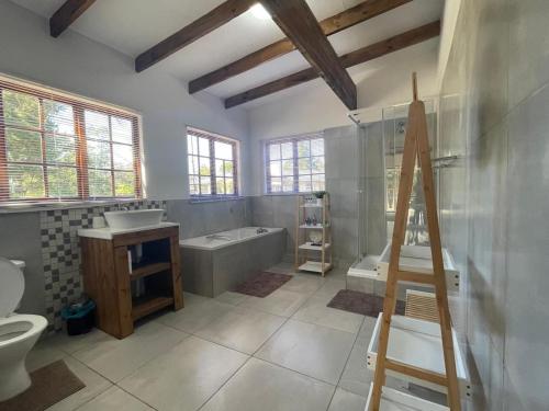 a bathroom with a tub and a sink and a toilet at Forest Gate Cabins in Plettenberg Bay