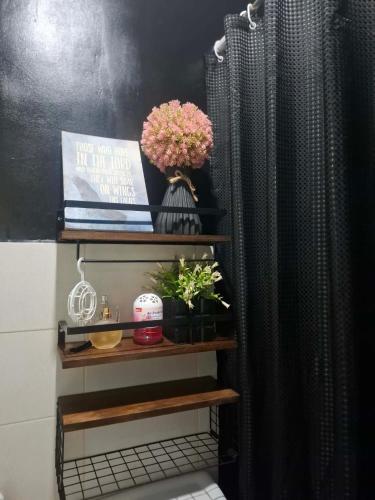 a bathroom with a shelf with flowers and a shower curtain at Lancaster new city in General Trias