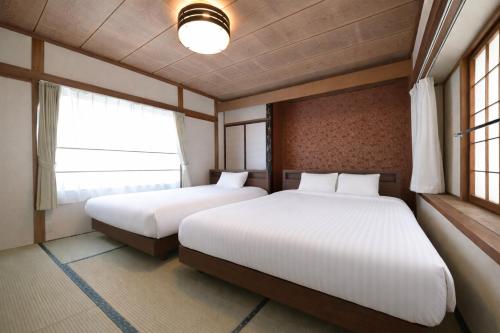 two beds in a room with two windows at APROSTAY Fuji-kawaguchiko Aizen15 in Fujiyoshida