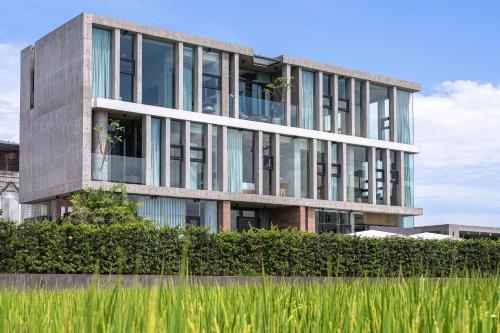 a tall building with glass windows in front of a field at 135 會館 135 Private Villa Yilan in Dongshan
