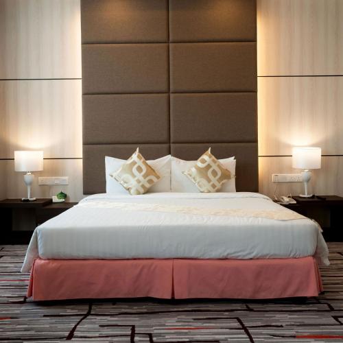 a bedroom with a large white bed with two lamps at Promenade Hotel Bintulu in Bintulu