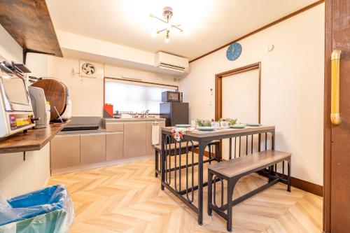 a kitchen with a table and bench in a room at Lax奈良 築65年和モダン古民家 一棟貸切 最大16名 専用ガレージ2台無料 自転車付き in Nara