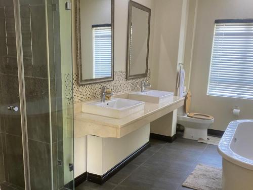 a bathroom with two sinks and a shower and a toilet at Riverfront Golf Estate House in Parys