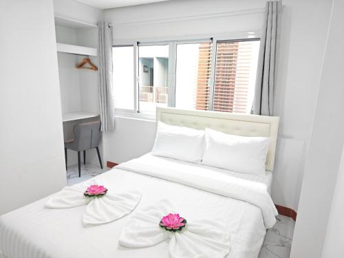 a bedroom with a white bed with pink flowers on it at Shwe Ooe Lay Guest House in Bangkok