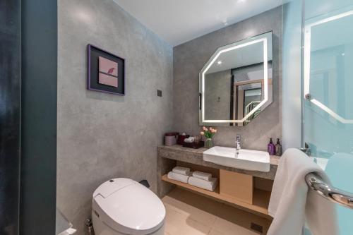 a bathroom with a toilet and a sink and a mirror at Mercure Qidong Downtown in Qidong