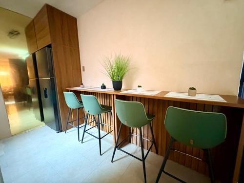 a kitchen with a bar with green chairs at Departamento tranquilo Huatulco in Santa Cruz Huatulco