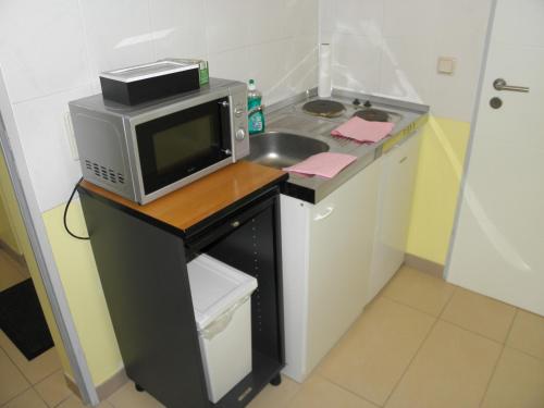 eine kleine Küche mit Mikrowelle und Spüle in der Unterkunft A&S FerienwohnungenBonner str 49 in Bonn