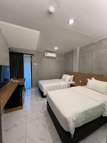 a hotel room with two beds and a flat screen tv at Tekoma Hotel Ipoh - Dandelion Inn in Simpang Pulai