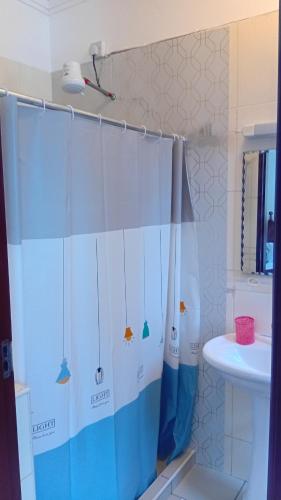 a bathroom with a shower curtain with a sink at Palm Comfort Apartment in Bamburi