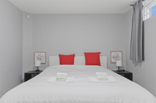 a bedroom with a white bed with red pillows at Central Van 1bedroom Suite in Vancouver