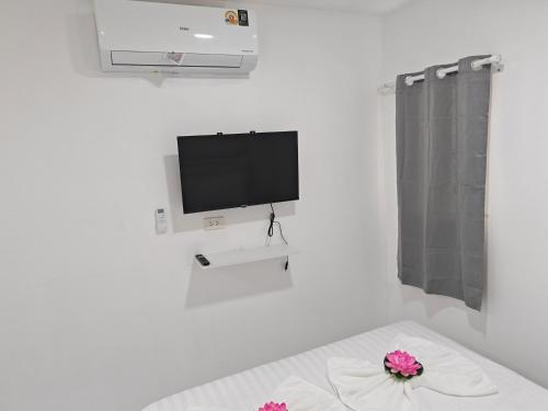 a white room with a tv and flowers on a bed at Shwe Ooe Lay Guest House in Bangkok