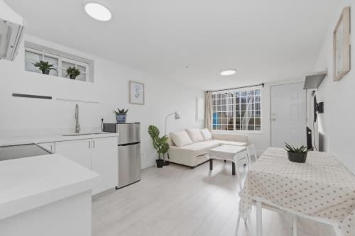 a white kitchen and living room with a table at Central Van 1bedroom Suite in Vancouver