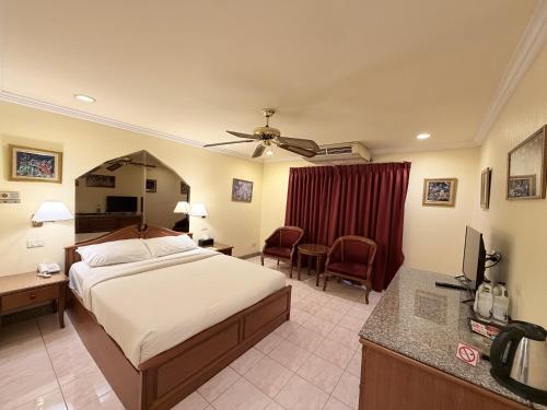 a bedroom with a bed and a desk with a television at Copa Hotel in Pattaya
