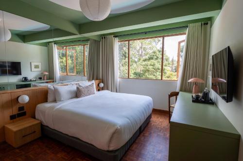 a bedroom with a large white bed and windows at Céline & Lolo in Nairobi