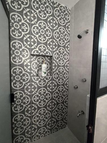 a shower stall with a black and white patterned wall at Casa colonial tranquila cerca del centro, Casa Solecito in Valladolid