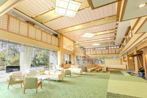 a large lobby with chairs and tables and windows at Ooedo Onsen Monogatari Premium Seiunkaku in Awara