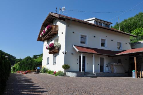 a white house with flower boxes on a cobblestone street at Garni San Paolo in Appiano sulla Strada del Vino