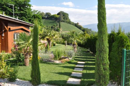 a garden with palm trees and a house at Garni San Paolo in Appiano sulla Strada del Vino
