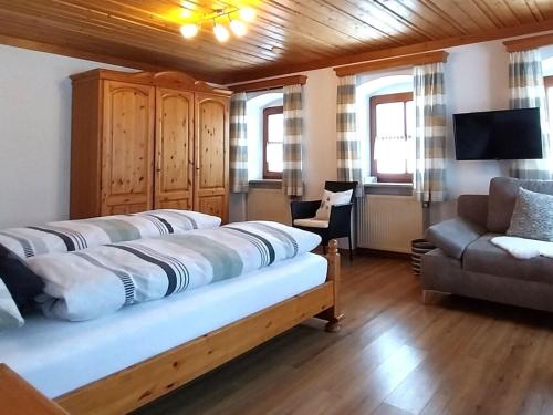 a bed in a room with a couch and a chair at Gschwandnerhof in Michelsneukirchen