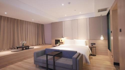 a bedroom with a white bed and a blue couch at Atour Hotel High Speed Railway North Station Zibo Hi tech Zone in Zibo