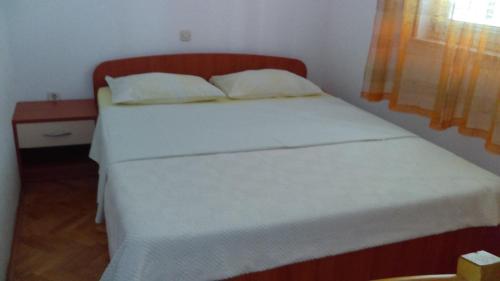 a bedroom with a white bed with a wooden headboard at Apartment Sunce in Crikvenica