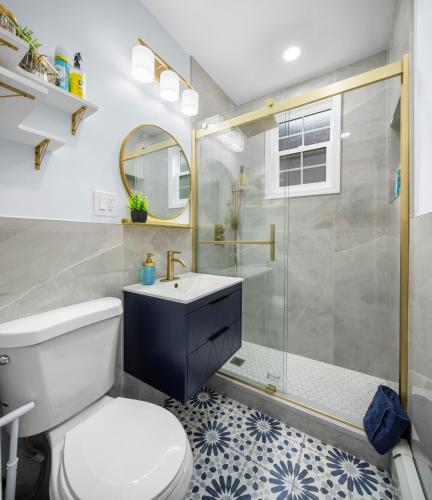 a bathroom with a shower and a toilet and a sink at Bright 2BR Retreat Walk to PATH NYC Access in Jersey City