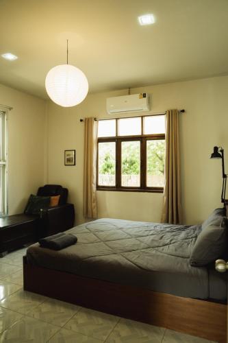 a bedroom with a bed and a couch and a window at บ้านมนต์รักเชียงดาว in Chiang Dao