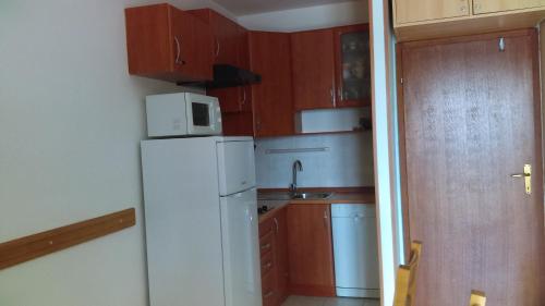 Elle comprend une petite cuisine équipée d'un réfrigérateur blanc et d'un évier. dans l'établissement Apartment Sunce, à Crikvenica