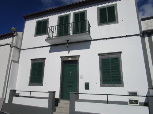 a white building with a green door and windows at Casa do Cruzeiro in Lagoa