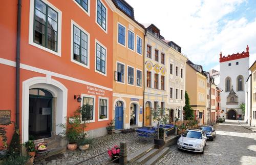eine Reihe von Gebäuden mit Autos, die auf einer Straße geparkt sind in der Unterkunft Haus Buchheim - Pension am Schloss in Bautzen